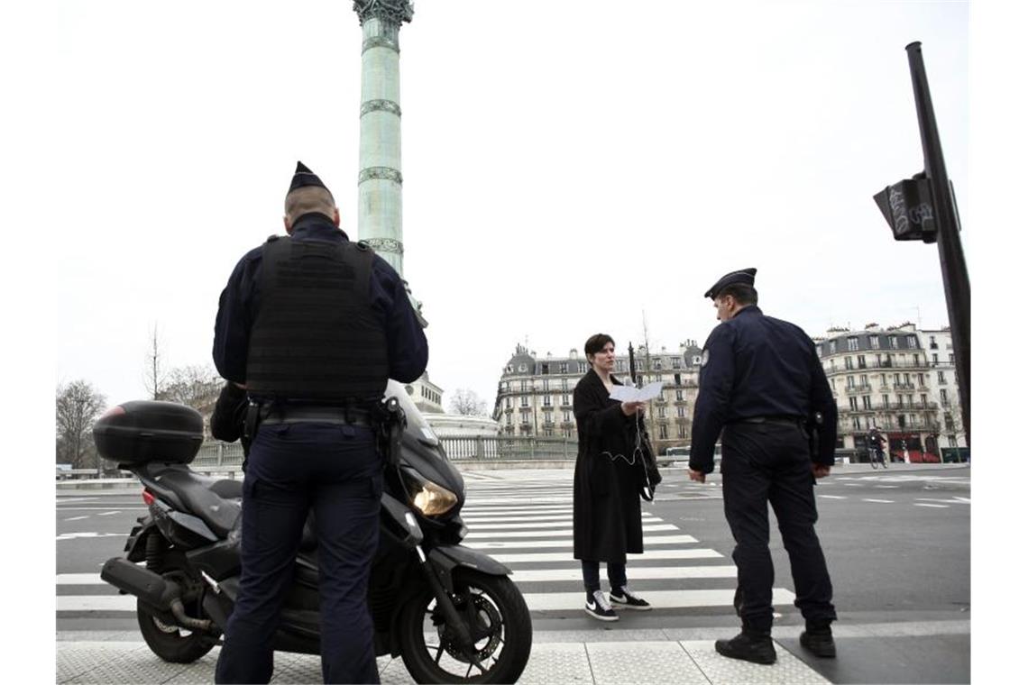 Ausgangssperren oder Appelle? Was Europa gegen Corona tut Polizeibeamte kontrollieren die Ausgangsformulare an einer Kontrollstelle in Paris. Foto: Thibault Camus/AP/dpa