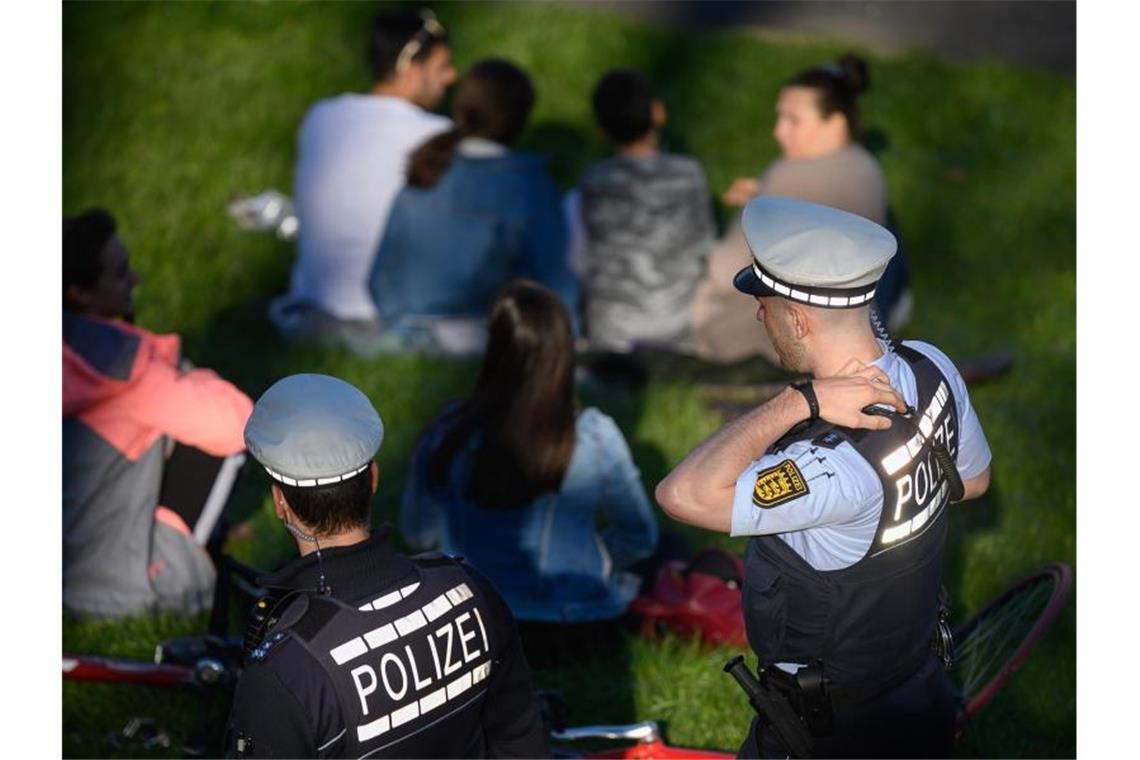 Polizeibeamte kontrollieren in einem Park die Einhaltung der Vorschriften zur Eindämmung des Coronavirus. Foto: Sebastian Gollnow/dpa/Archivbild