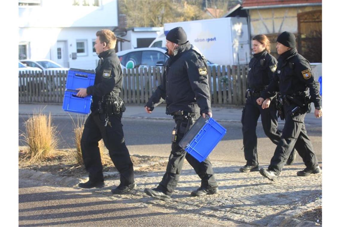 Ermittler durchsuchen Häuser von Sondengängern: Waffenfund Polizeibeamte überqueren mit blauen Kisten in den Händen eine Straße. Foto: Ralf Zwiebler/dpa