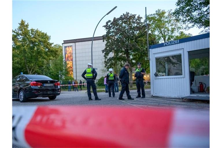 Polizeibeamte und Zivilisten stehen im abgesperrten Bereich vor der Synagoge in Hamburg-Harvestehude. Foto: Jonas Walzberg/dpa