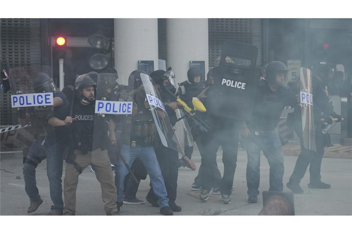 Polizeibeamte versammeln sich, während Tränengas die Luft füllt, während eines Protests, nachdem die Bundeseinwanderungsbehörden in Los Angeles eine Operation durchgeführt haben.