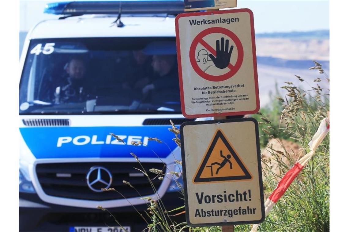 Polizeifahrzeug am Tagebau Garzweiler neben Warnschildern mit den Aufschriften „Werksanlagen“. Foto: David Young
