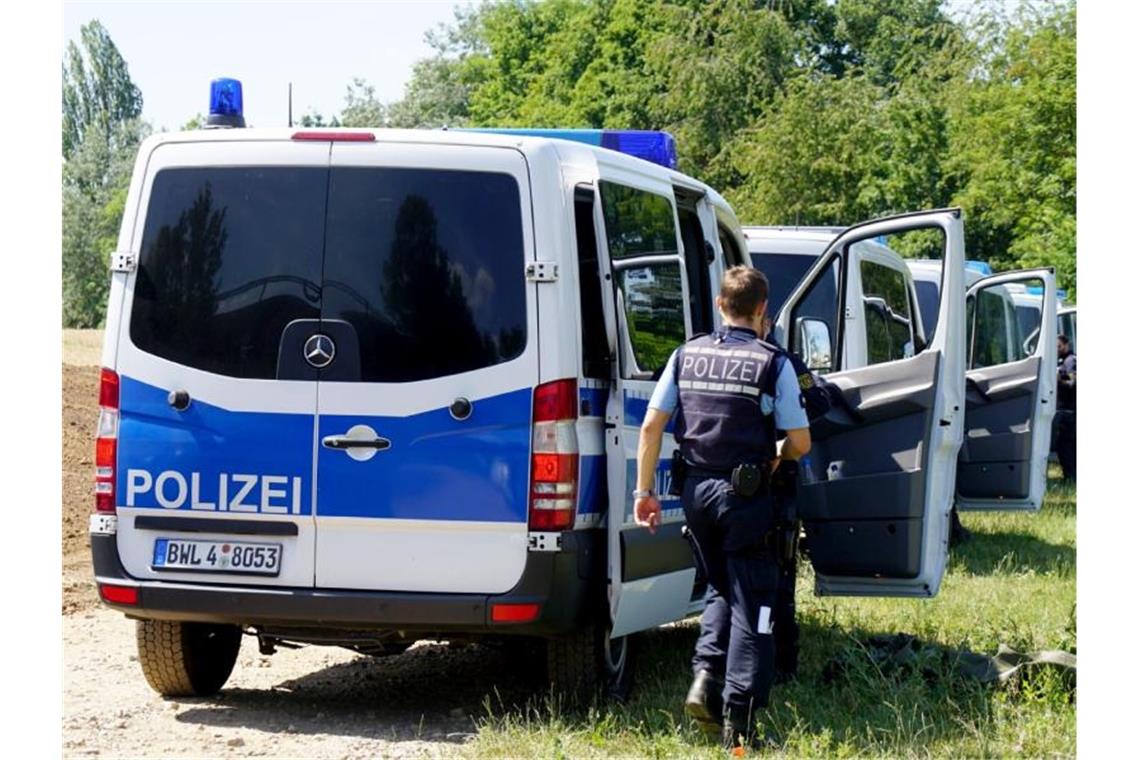 Polizeifahrzeuge stehen an einem Weg. Foto: Sven Kohls/Archivbild