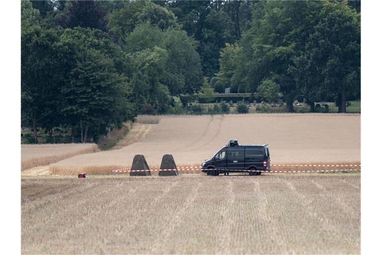 Polizeifahrzeuge vor einer Kleingarten-Parzelle, die von Beamten durchsucht wird. Foto: Peter Steffen/dpa