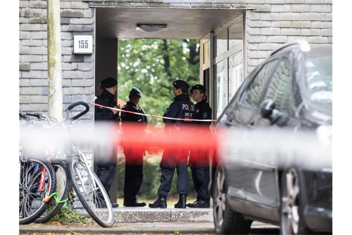 Polizisten beraten vor dem Eingang des Wohnhauses, in dem die Kinder gefunden wurden. Foto: Marcel Kusch/dpa