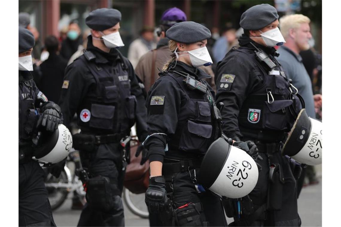 Polizisten bewachen eine Demonstration am Rosa-Luxemburg-Platz mit Mundschutz. Foto: Christoph Soeder/dpa
