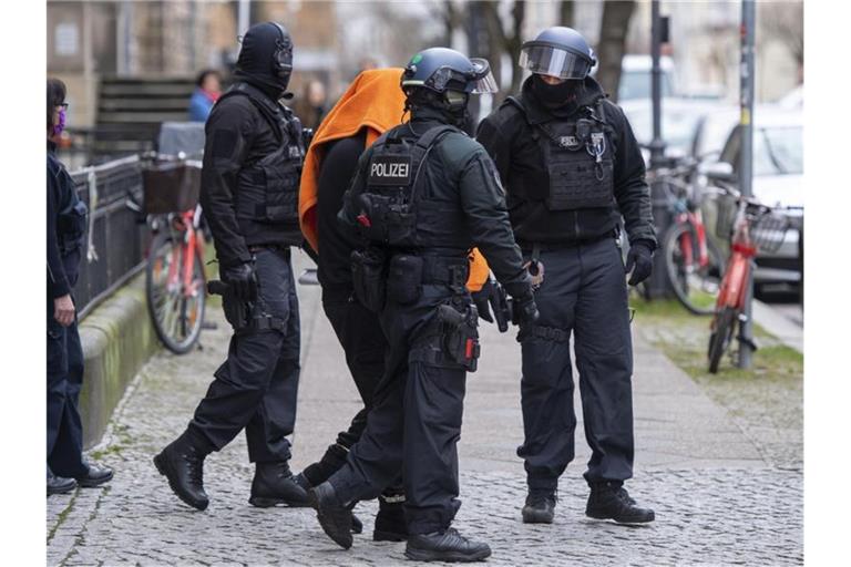 Polizisten bringen den Angeklagten unter einer Decke aus dem Gerichtsgebäude in Berlin. Foto: Christophe Gateau/dpa