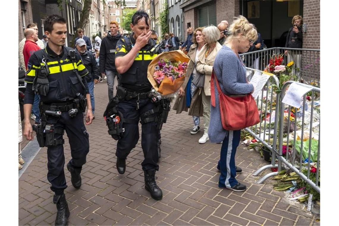 Polizisten bringen einen Blumenstrauß zu dem Blumenmeer für den Reporter Peter R. de Vries in der Leidswarsstraat. Foto: Evert Elzinga/ANP/dpa