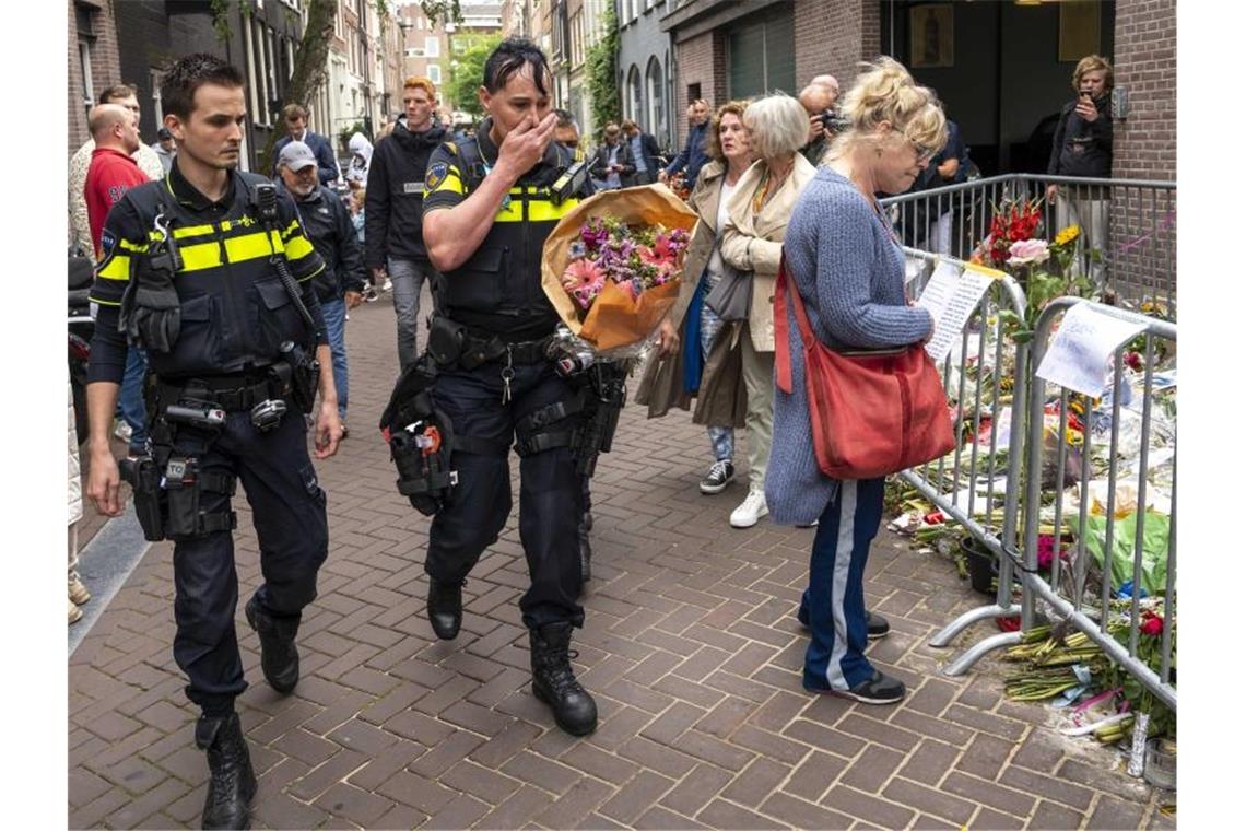 Niederländischer Reporter nach Mordanschlag gestorben Polizisten bringen einen Blumenstrauß zu dem Blumenmeer für den Reporter Peter R. de Vries in der Leidswarsstraat. Foto: Evert Elzinga/ANP/dpa
