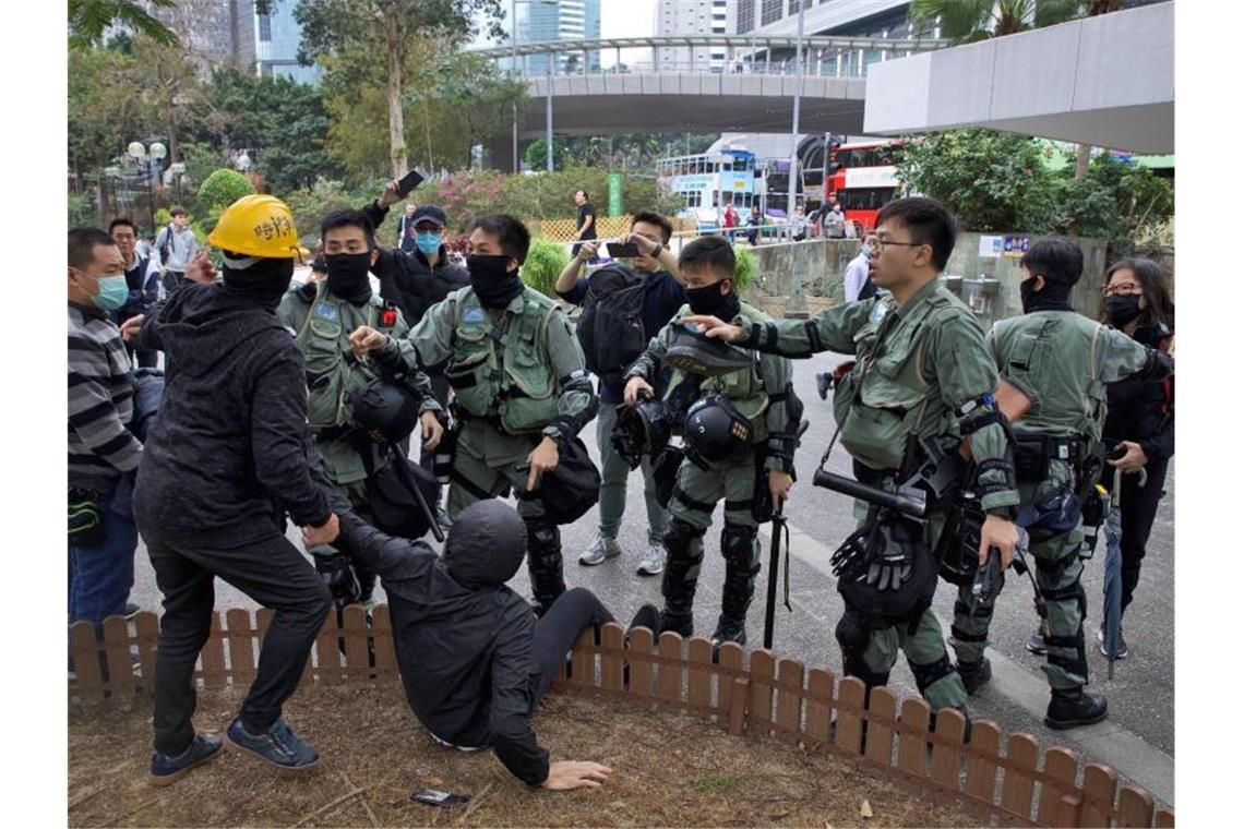 Hongkongs Polizei stoppt Marsch von Zehntausenden mit Gewalt Polizisten drängen zwei Demonstranten ab. Foto: Ng Han Guan/AP/dpa