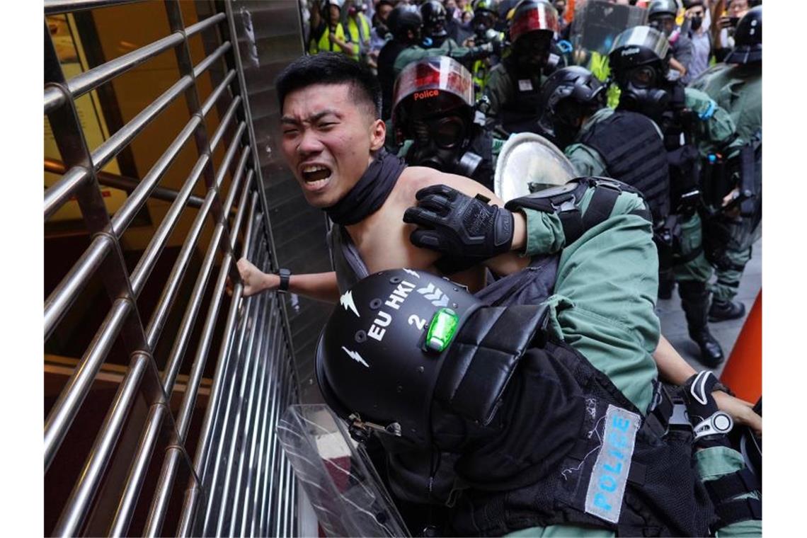 Polizisten drücken einen Demonstranten gegen ein Gitter. Foto: Vincent Yu/AP/dpa