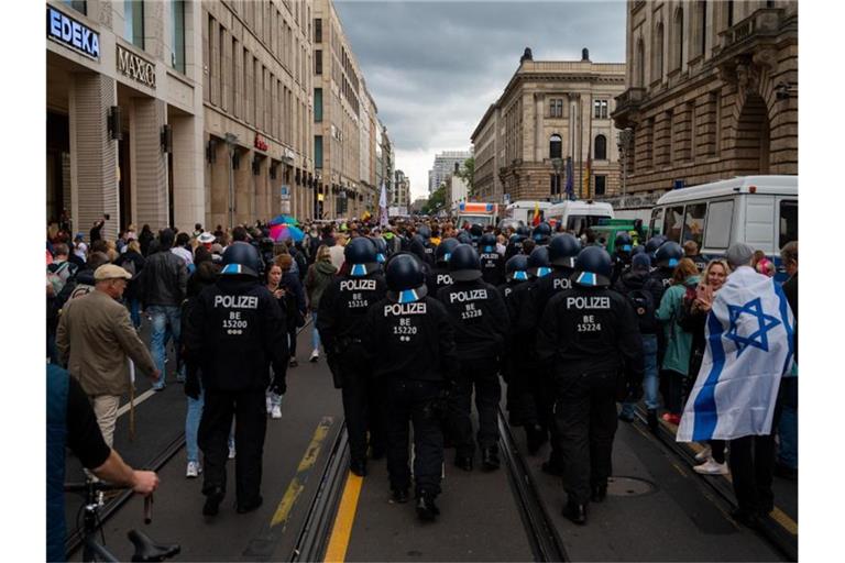 Polizisten folgen nach dem Ende einer Kundgebung gegen die Corona-Politik der Regierung den Teilnehmern. Foto: Paul Zinken/dpa
