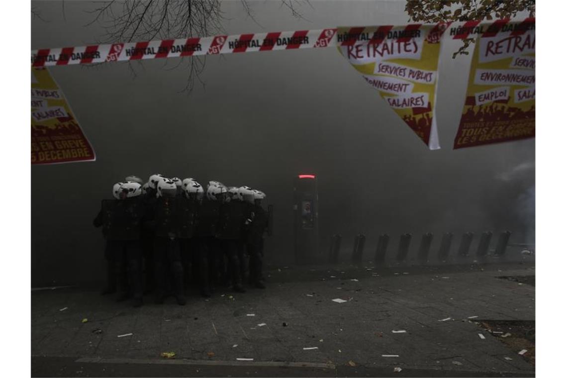 Polizisten formieren sich in Paris inmitten einer dichten Rauchwolke. Foto: Rafael Yaghobzadeh/AP/dpa