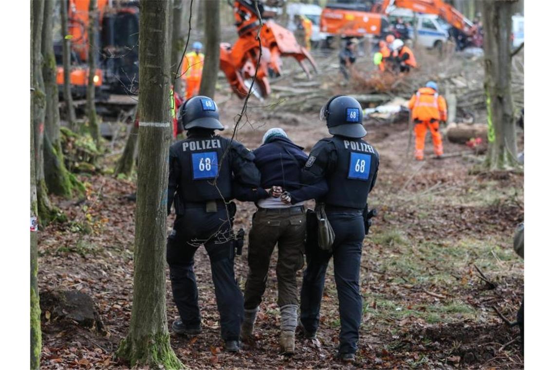 Polizei in Baumhaus-Camp im Dannenröder Forst Polizisten führen eine A49-Gegnerin durch ein bereits gerodetes Waldgebiet. Foto: Nadine Weigel/dpa