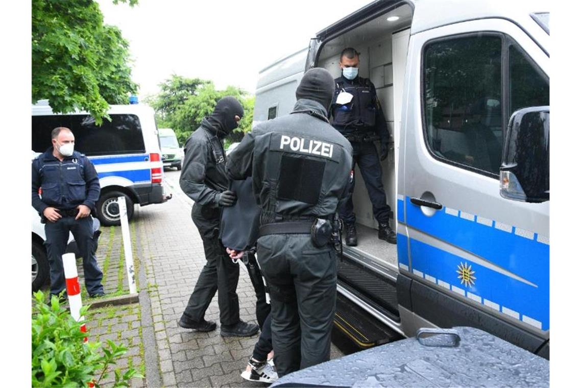 Mutmaßlicher Drogenring ausgehoben: 13 Tatverdächtige Polizisten führen einen Mann zu einem Einsatzfahrzeug. Foto: Rene Priebe/pr-video/dpa