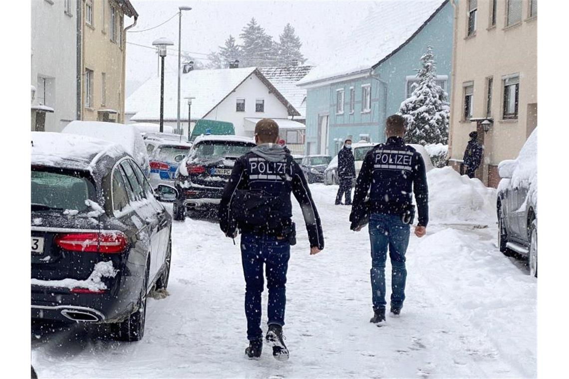 Polizisten gehen auf einer verschneiten Straße in einem Wohngebiet zu einem Tatort, an dem eine Frau nach einer Auseinandersetzung mit ihrem Ehemann gestorben ist. Foto: Andreas Maier/dpa
