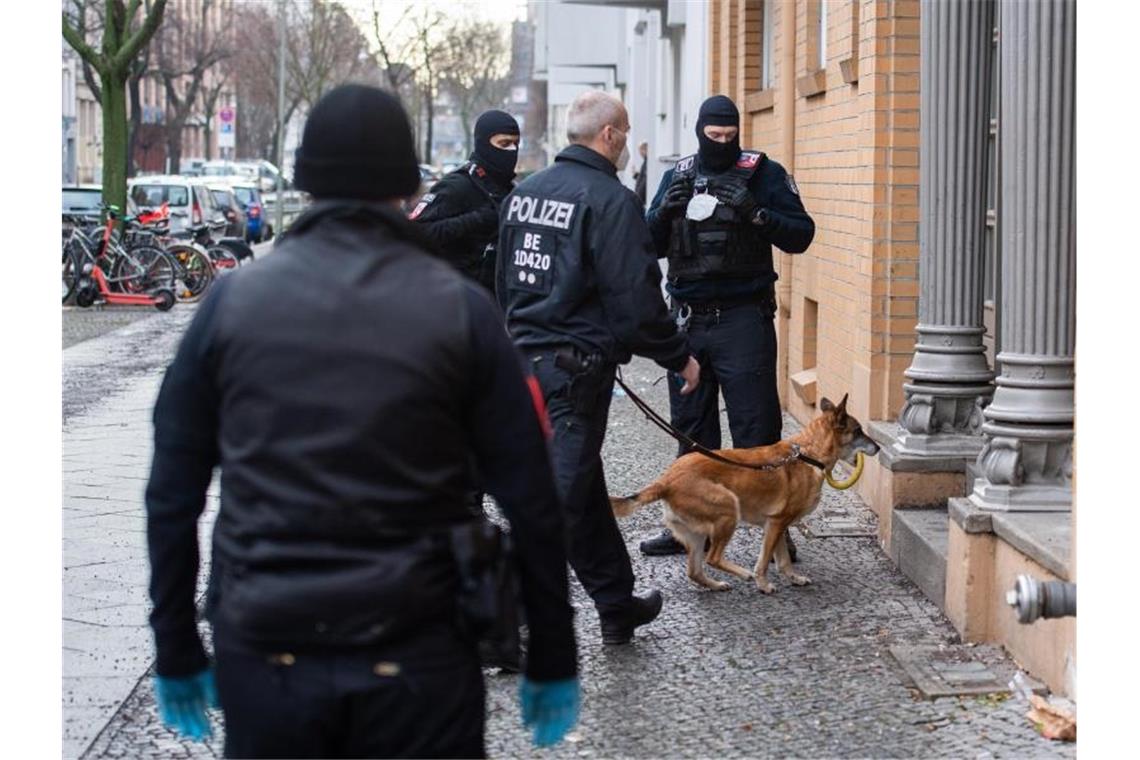Polizisten gehen bei einer Razzia mit einem Hund in ein Haus. Foto: Christophe Gateau/dpa