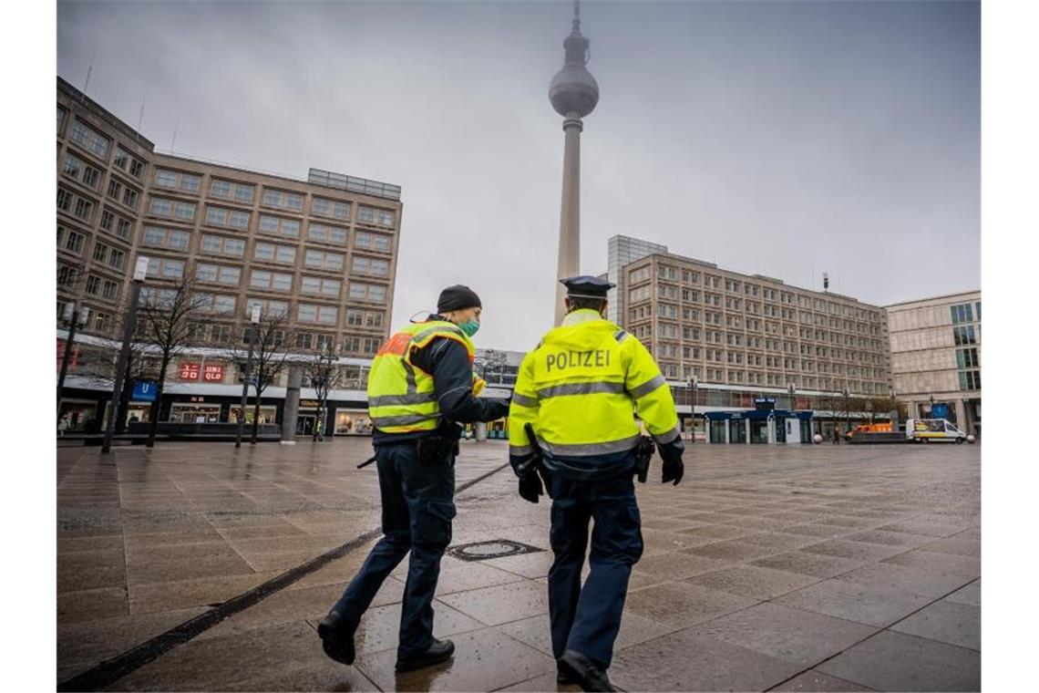 Polizisten gehen über den ansonsten weitgehend leeren Alexanderplatz in der Hauptstadt. Die meisten Geschäfte müssen im Lockdown geschlossen bleiben. Foto: Michael Kappeler/dpa