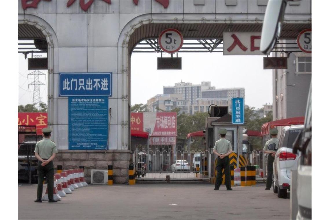 China meldet 57 neue Corona-Infizierte Polizisten halten vor den barrikadierten Eingängen des Xinfadi-Großmarktes Wache. Foto: Mark Schiefelbein/AP/dpa