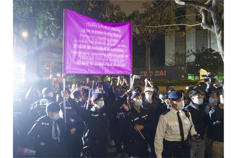 Polizisten hissen vor einem Gericht in Hongkong eine Warnflagge gegen die Unterstützer von 47 pro-demokratischen Aktivisten, die wegen angeblicher Verstöße gegen das neue Sicherheitsgesetz vorerst in Untersuchungshaft bleiben müssen. Foto: Vincent Yu/AP/dpa