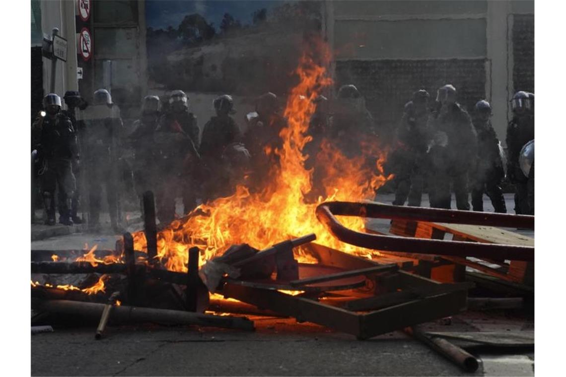 Polizisten in Hongkong hinter einer brennenden Barrikade. Foto: Vincent Yu/AP