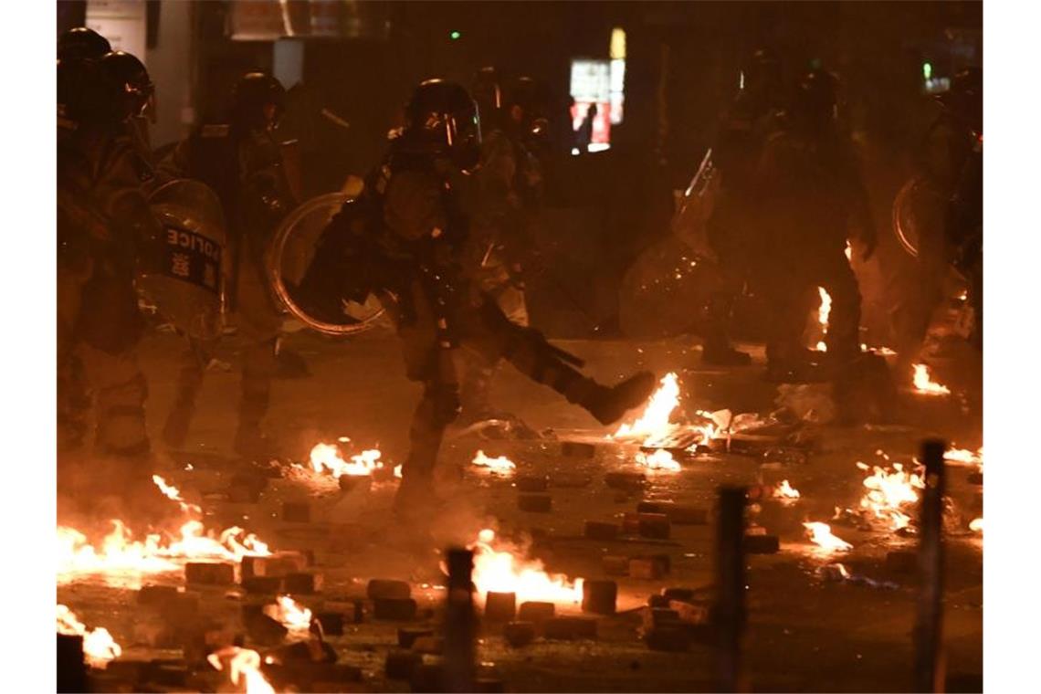 Polizisten in Schutzausrüstung stehen zwischen den Resten von Molotowcocktails. Foto: -/kyodo/dpa