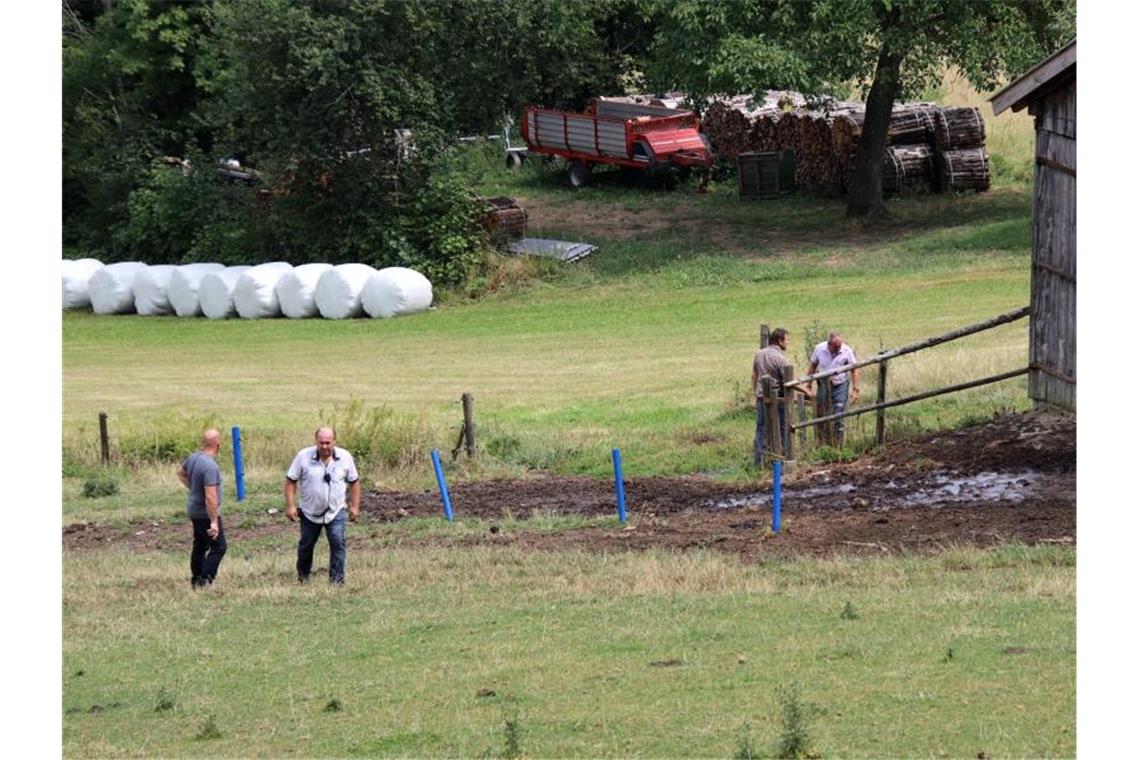 Polizisten in Zivil stehen auf einer Weide, auf der zuvor ein Stier zwei Menschen getötet hatte. Foto: Alexander Auer