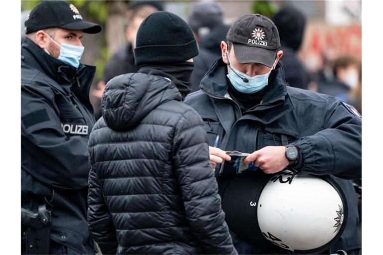 Polizisten kontrollieren die Personalien von einem Teilnehmer einer Demonstration in Hamburg. Foto: Axel Heimken/dpa