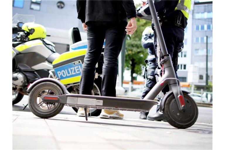 Polizisten kontrollieren einen E-Tretroller-Fahrer. Foto: Martin Gerten/dpa/Symbolbild