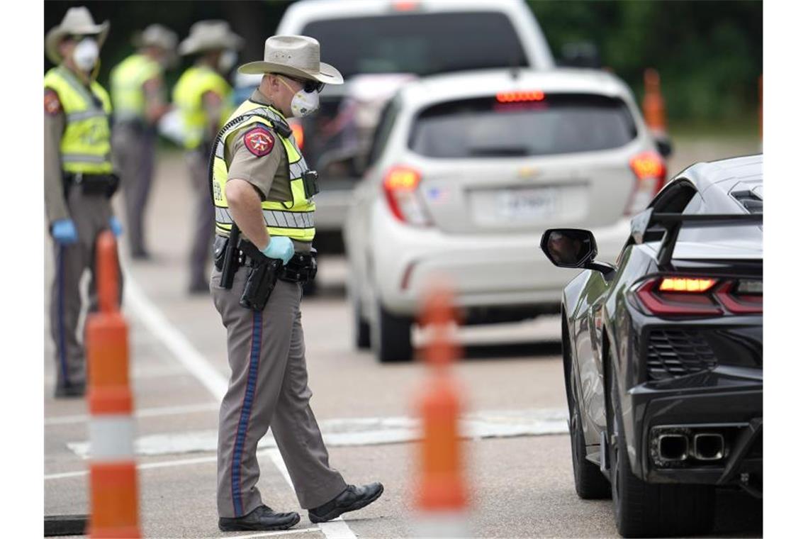Polizisten kontrollieren kontrollieren Autofahrer bei der Einreise von Louisiana nach Texas, um zu überprüfen, ob diese sich in eine 14-tägige Selbstquarantäne begeben müssen. Foto: David J. Phillip/AP/dpa