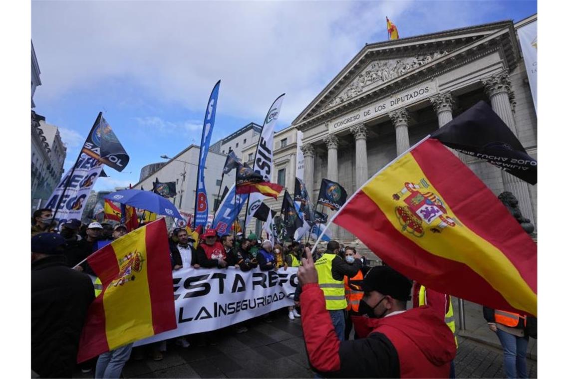 Polizisten laufen während des Protestmarsches am spanischen Parlament in Madrid vorbei. Foto: Paul White/AP/dpa