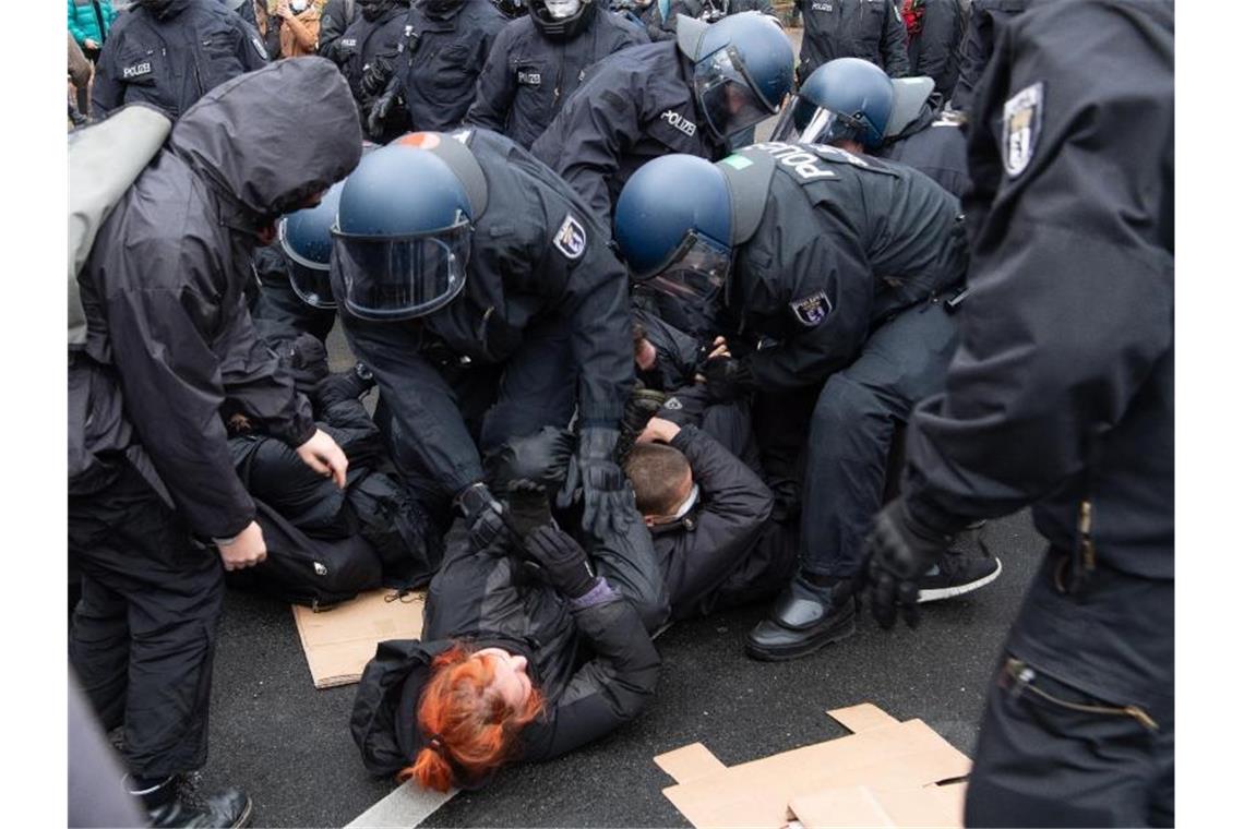 Polizisten lösen eine Sitzblockade von Gegen-Demonstranten auf. Foto: Paul Zinken/dpa