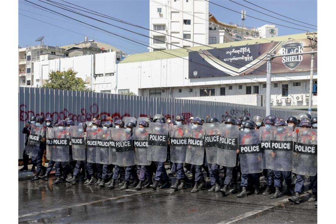 Polizisten mit Schutzschilden blockieren eine Demonstration an einer Kreuzung in Mandalay. Foto: Str/AP/dpa