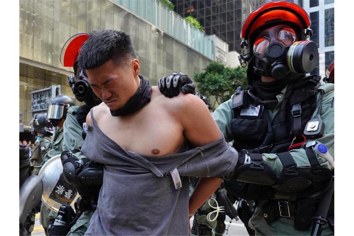 Polizisten nehmen einen Demonstranten fest. Foto: Vincent Yu/AP/dpa
