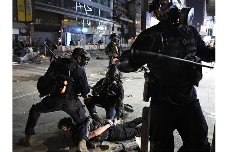 Polizisten nehmen in der Nähe der Polytechnischen Universität einen Demonstranten fest. Foto: -/kyodo/dpa