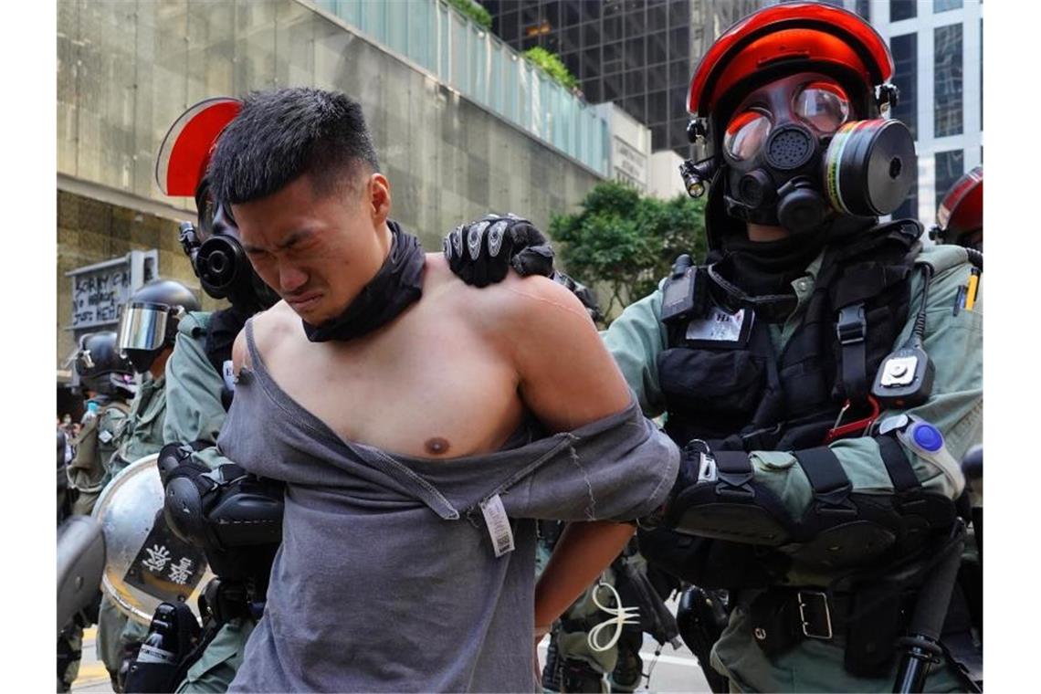 Demonstrant angeschossen: Neue Gewaltwelle in Hongkong Polizisten nehmen in martialischer Ausrüstung einen Demonstranten fest. Foto: Vincent Yu/AP/dpa