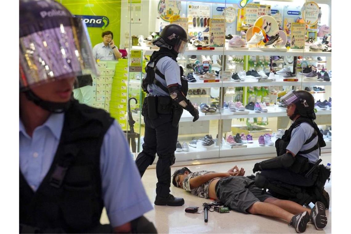Polizei verhindert Proteste in Hongkong Polizisten nehmen vor einem Schuhladen einen Mann fest. Foto: Vincen Yu/AP