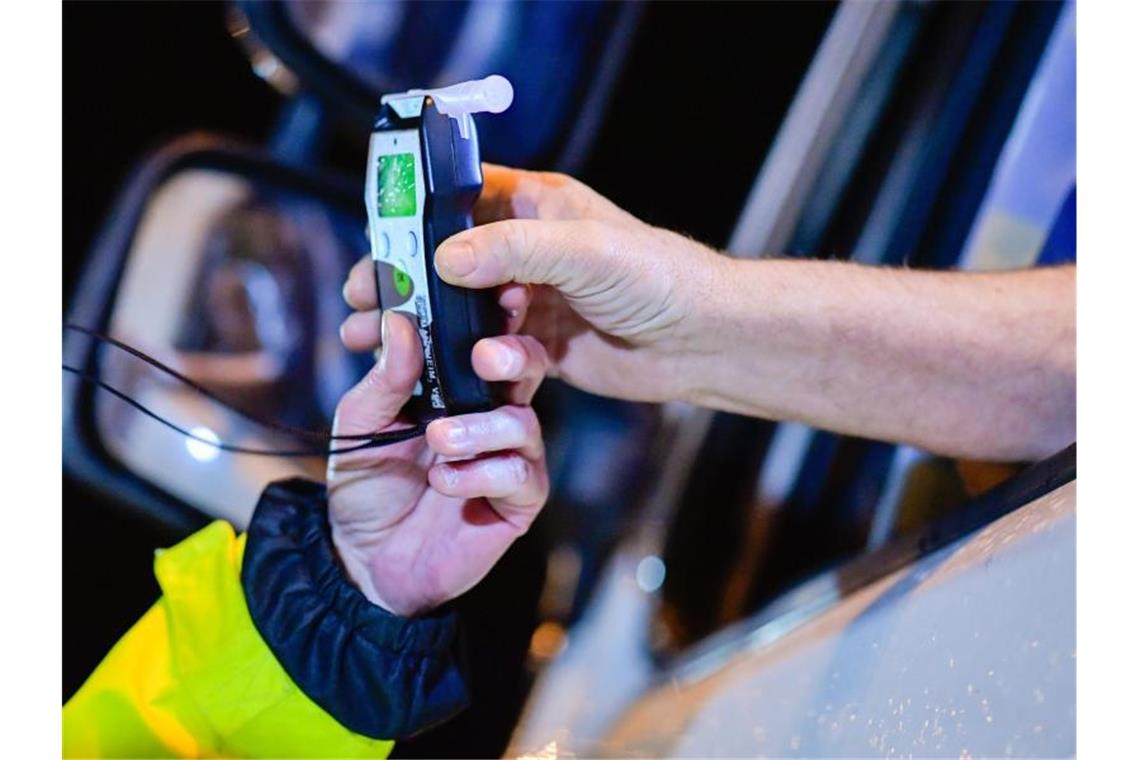 Polizisten reichen ein Alkoholmessgerät in eine Fahrerkabine. Foto: Uwe Anspach/dpa/Symbolbild