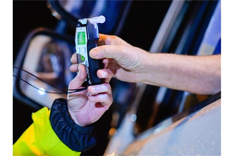 Polizisten reichen ein Alkoholmessgerät in eine Fahrerkabine. Foto: Uwe Anspach/dpa/Symbolbild