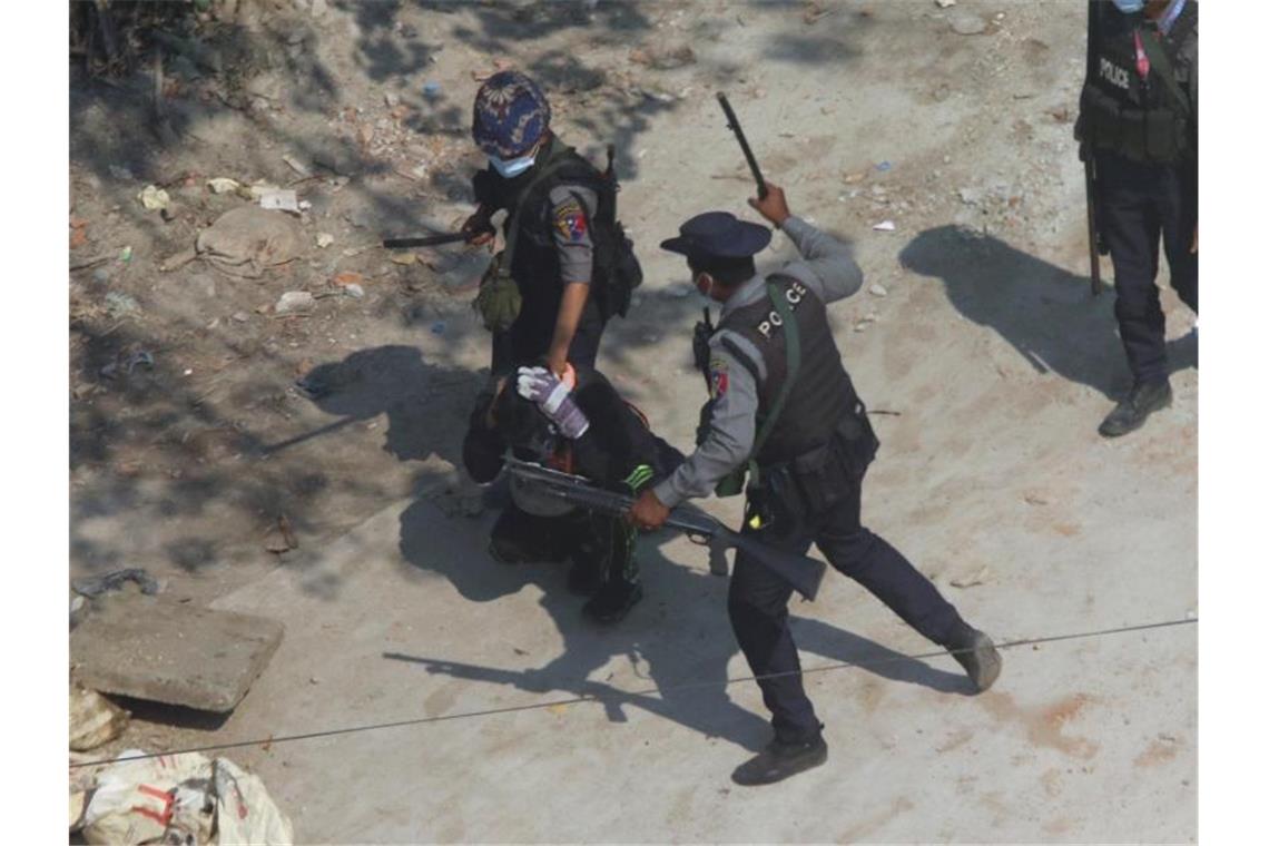 Proteste in Myanmar fortgesetzt - Polizei greift durch Polizisten schlagen mit Knüppeln auf einen Demonstranten am Stadtrand von Yangon (ehemals Rangoon) ein. Foto: -/AP/dpa