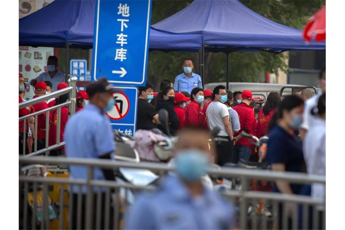 Corona-Ausbruch auf Großmarkt in Peking Polizisten sichern einen Fleischmarkt, der von den Behörden geschlossen wurde, nachdem bekannt wurde, dass ein Besucher des Marktes positiv auf das Coronavirus getestet worden war. Foto: Mark Schiefelbein/AP/dpa