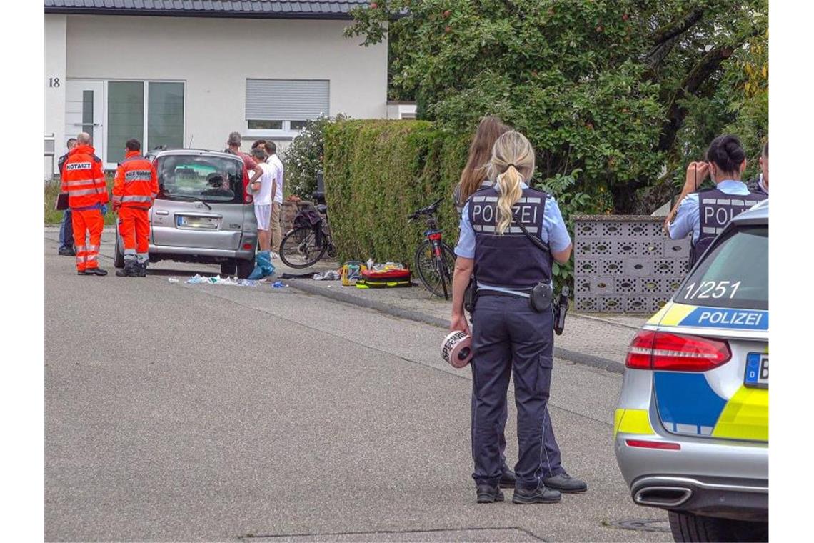 Nach Streit unter Brüdern: 29-Jähriger weiter in Lebengefahr Polizisten sperren eine Straße ab, in der Rettungssanitäter neben einem PKW stehen. Foto: Fabian Geier/dpa/Archivbild