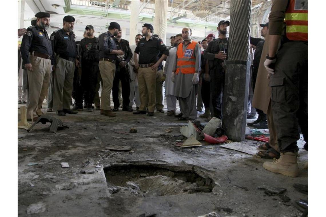 Polizisten stehen am Ort der Explosion in der Koranschule in Peshawar. Foto: Muhammad Sajjad/AP/dpa