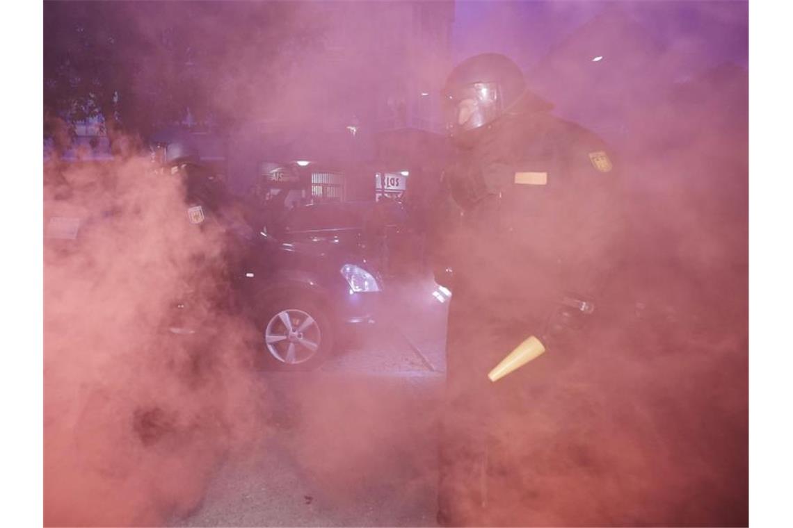 Polizisten stehen am Rande der Demonstration im Rauch von Pyrotechnik. Foto: Michael Kappeler/dpa