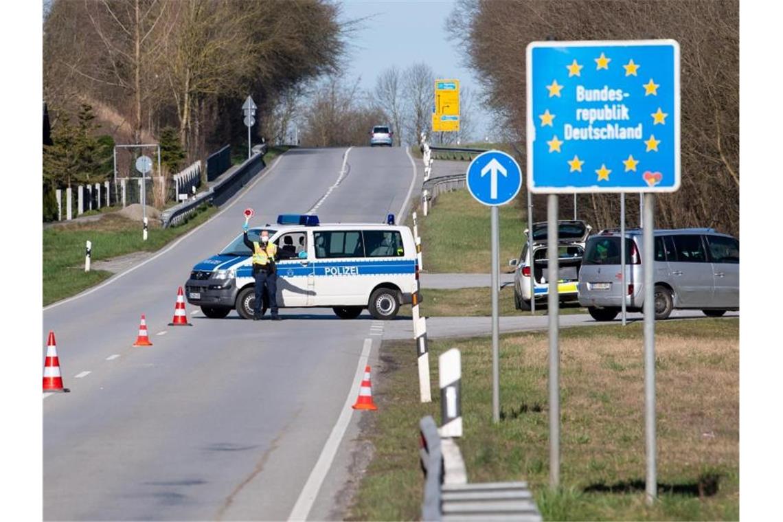 Polizisten stehen an der Bundesstraße 512 in der Nähe von Neuhaus am Inn an einer Kontrollstelle an der Grenze zu Österreich. Foto: Sven Hoppe/dpa