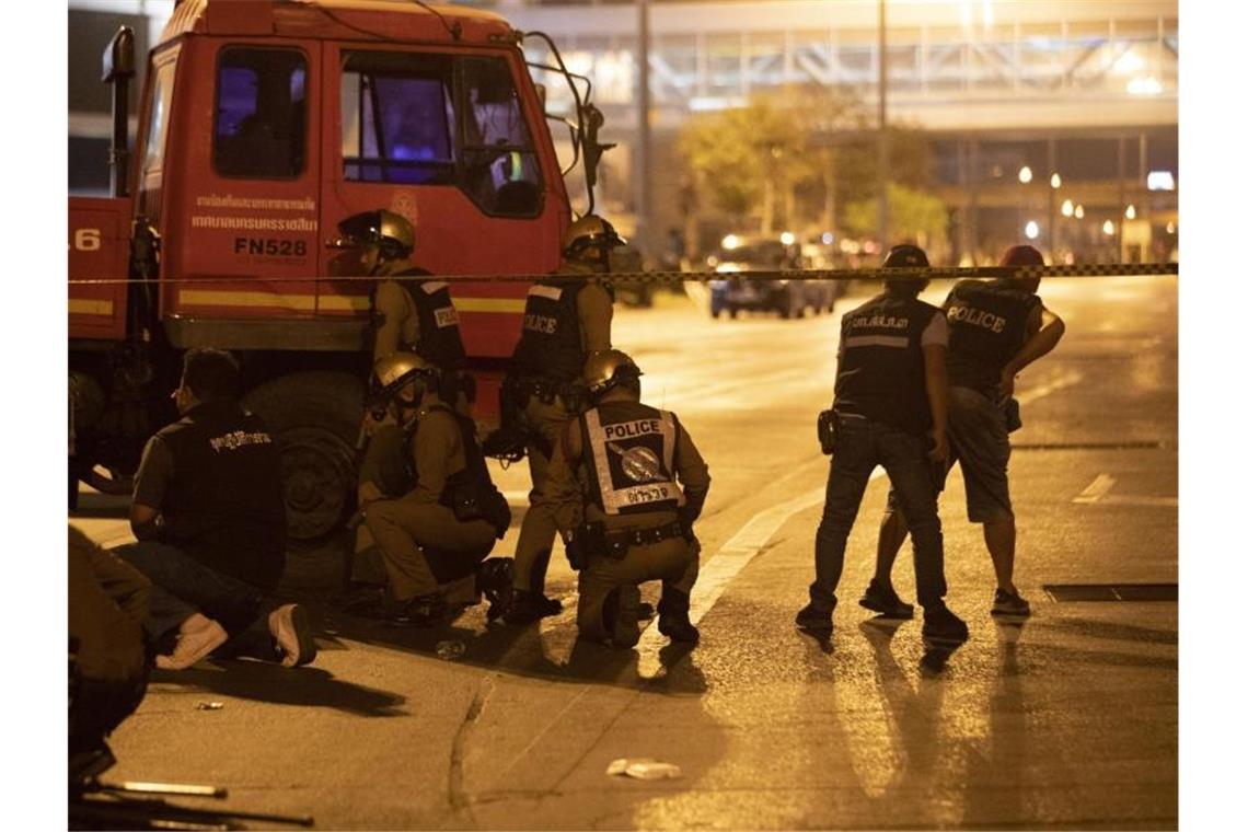 Polizisten stehen hinter einem Lastwagen vor dem Einkaufszentrum Terminal 21. Foto: Sakchai Lalitkanjanakul/AP/dpa