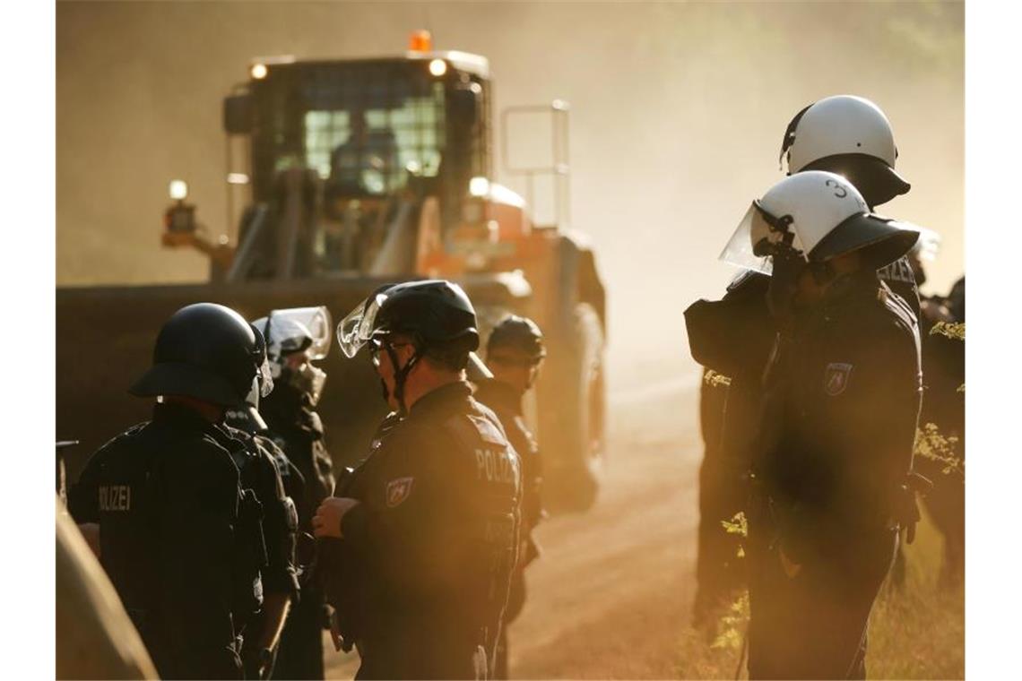 Polizisten stehen im Hambacher Forst neben einer Planierraupe. Foto: David Young/dpa