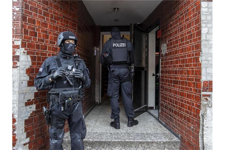 Polizisten stehen in einem Hauseingang im Stadtteil Laar. Foto: Christoph Reichwein/dpa