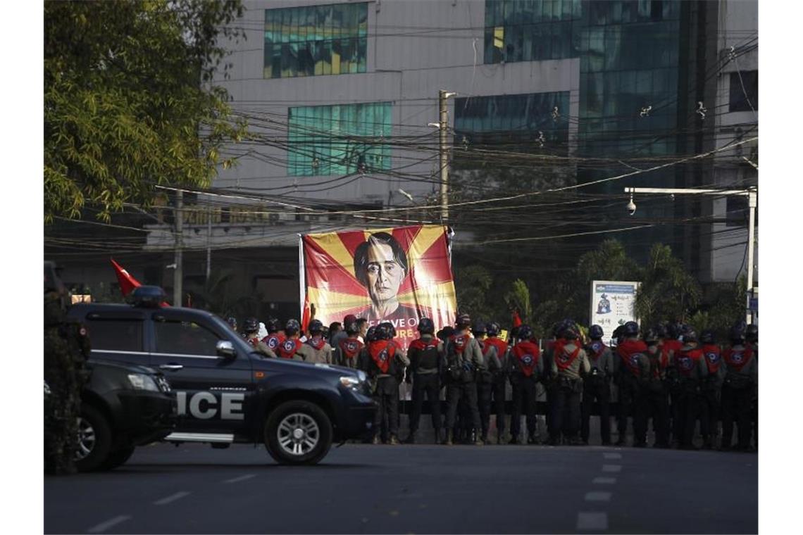 Polizisten stehen in Rangun vor Teilnehmern eines Protestes gegen den jüngsten Militärputsch. Auf einem großen Transparent: das Bild der Regierungschefin Suu Kyi. Foto: Uncredited/AP/dpa