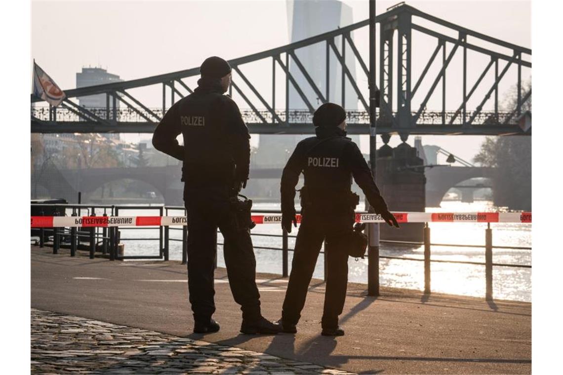 Polizisten stehen morgens vor dem Eisernen Steg an einer Absperrung am Mainufer. Foto: Frank Rumpenhorst